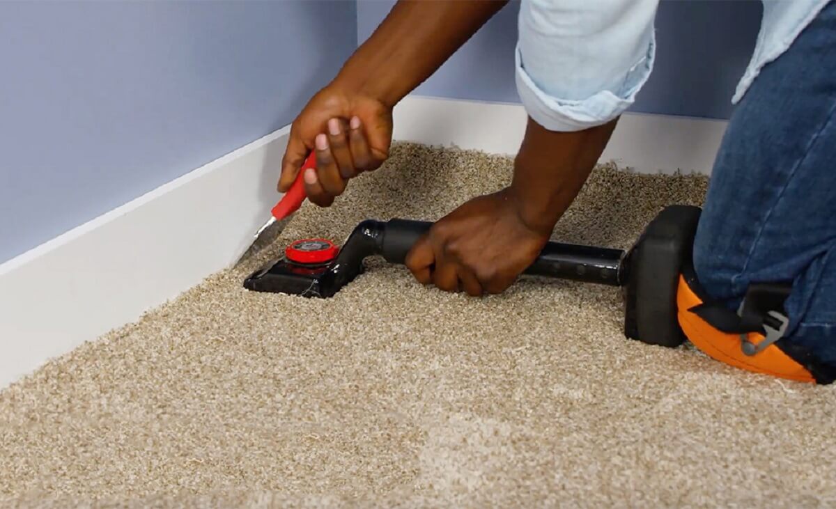 Installer securing carpet near a wall